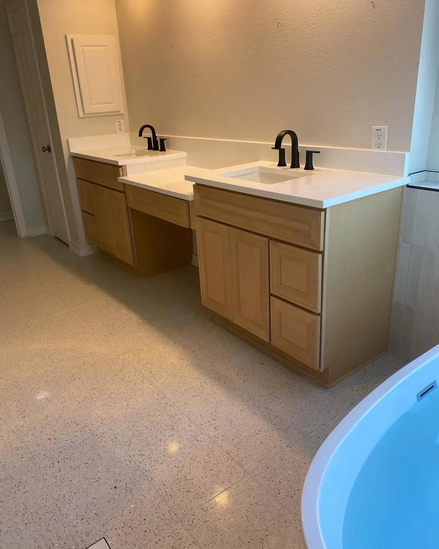 Dual-sink vanity with wood cabinets, white quartz countertop, black faucets, and tile backsplash