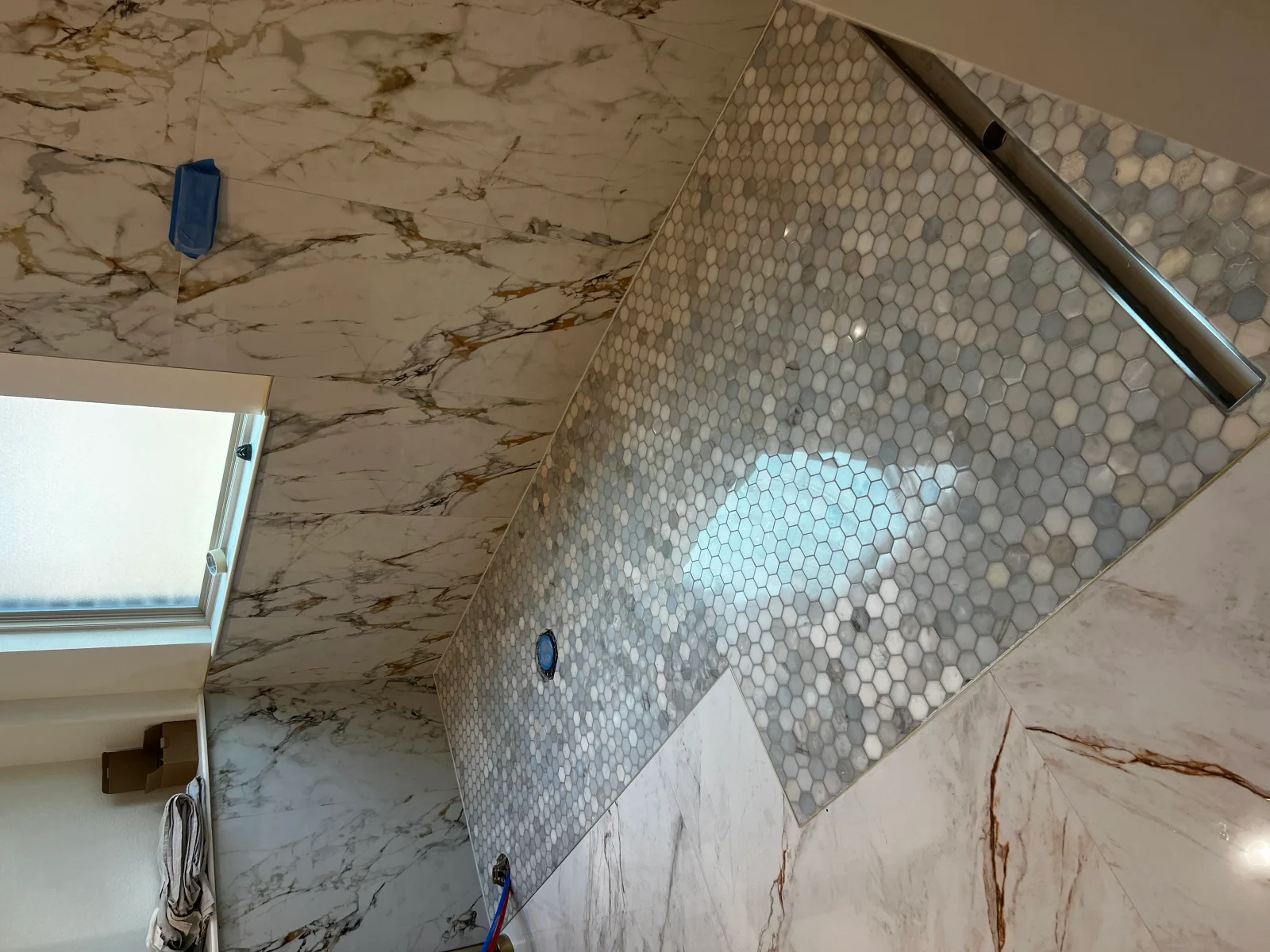 Marble tile ceiling and walls with hexagonal mosaic accent, chrome trim, bathroom installation