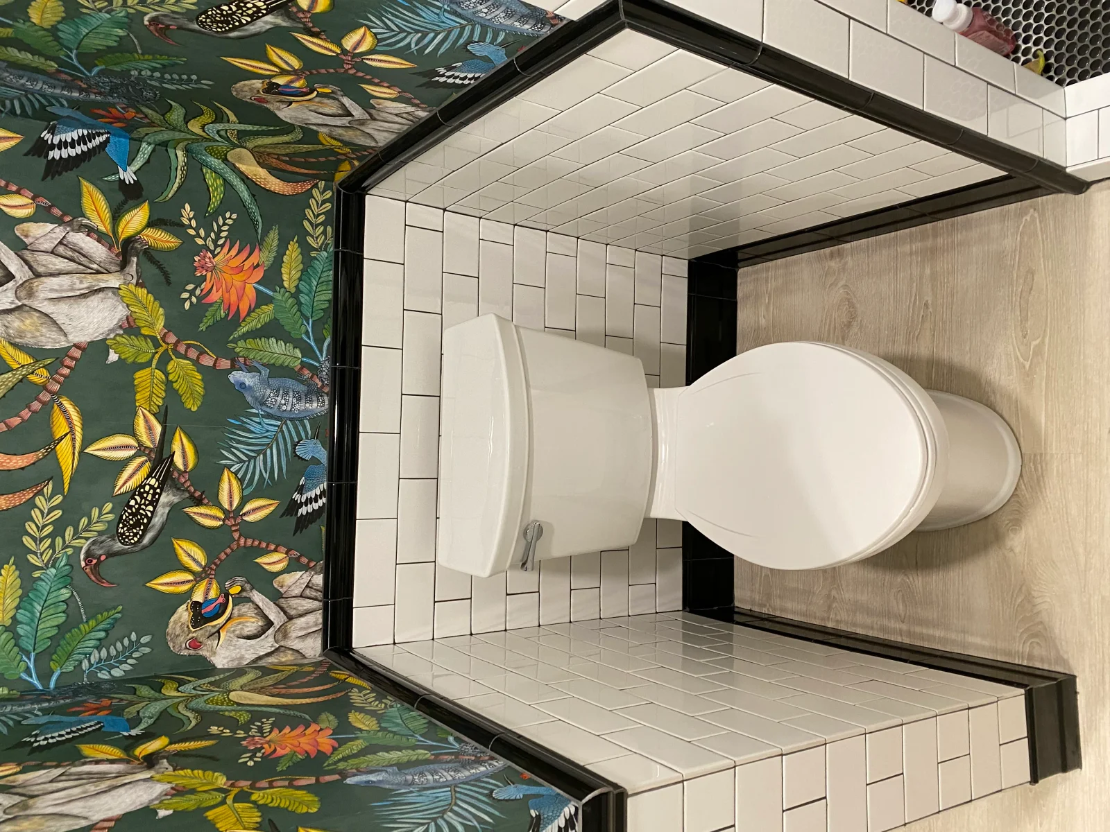 White subway tile bathroom with wood-look accents and green botanical feature wall