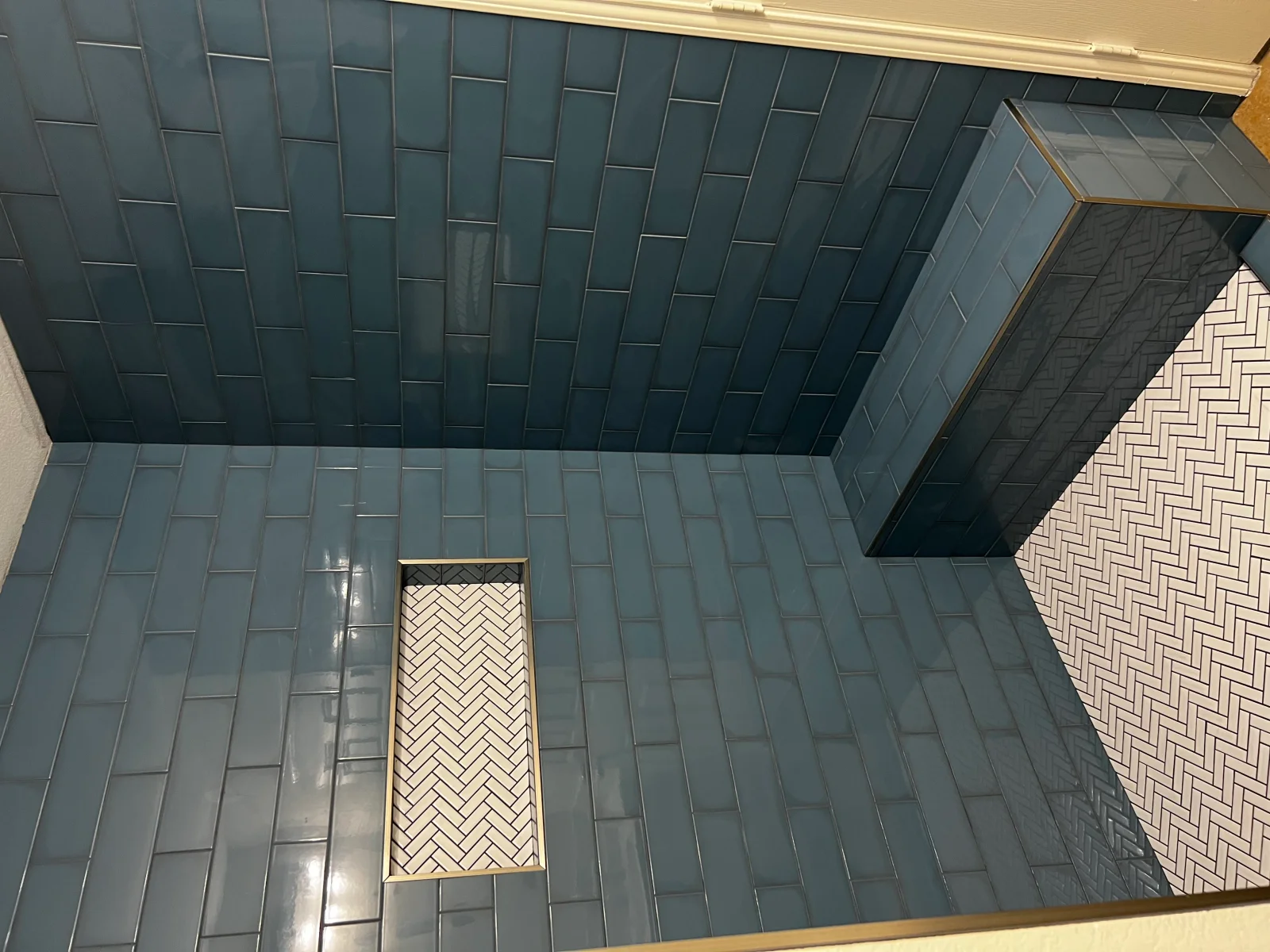 Stacked subway tile walls with herringbone accent tile and brass trim in bathroom