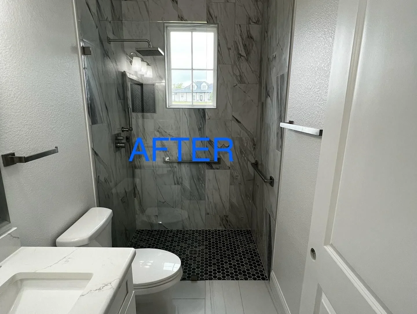 Gray marble tile shower walls with black hexagonal floor tile and frameless glass enclosure