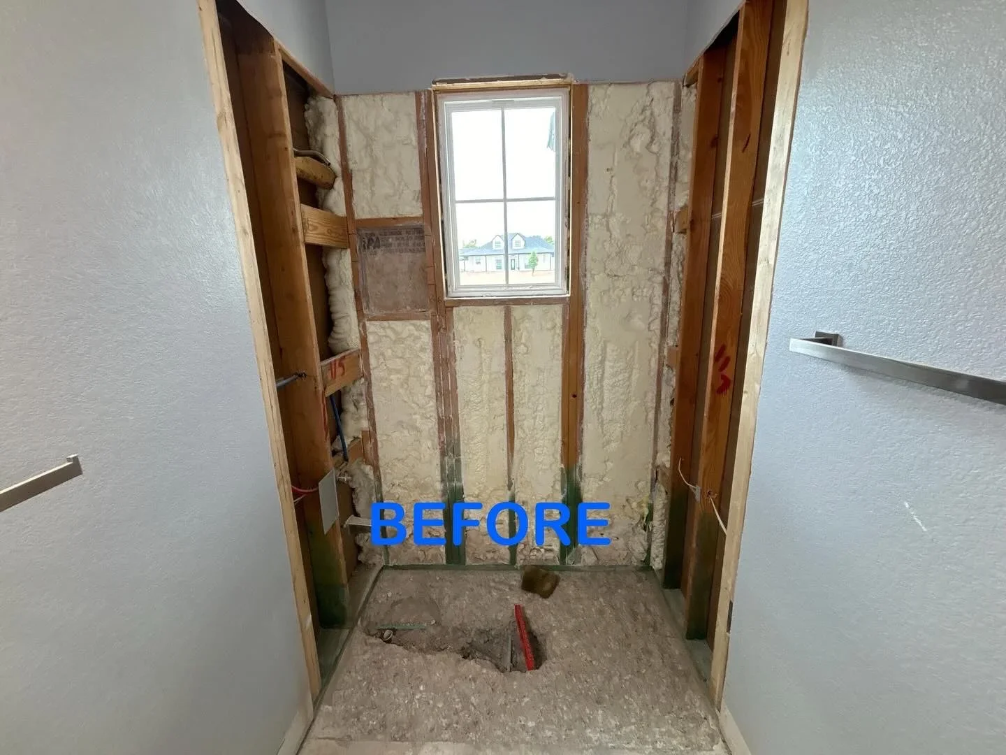 Bathroom shower framing with insulation, wooden studs, and window opening before tile installation