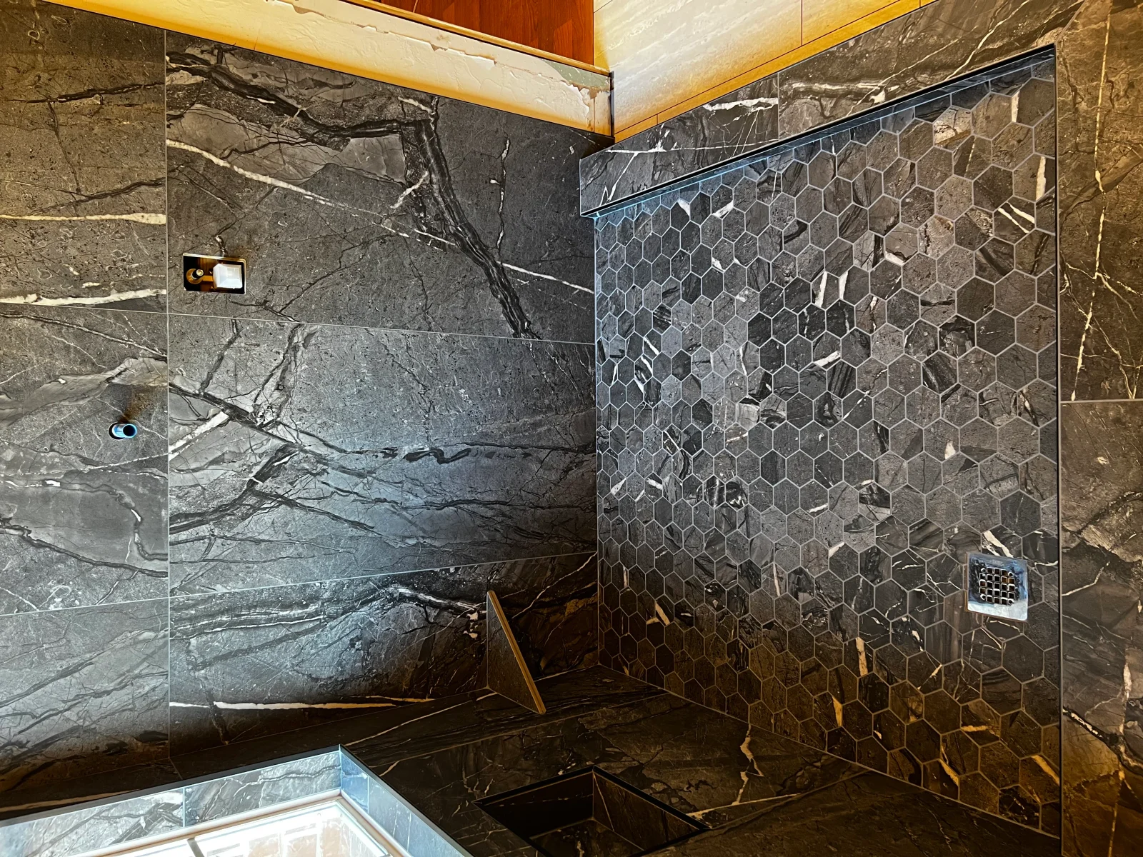 Marble slab and hexagonal mosaic tile shower with frameless glass enclosure