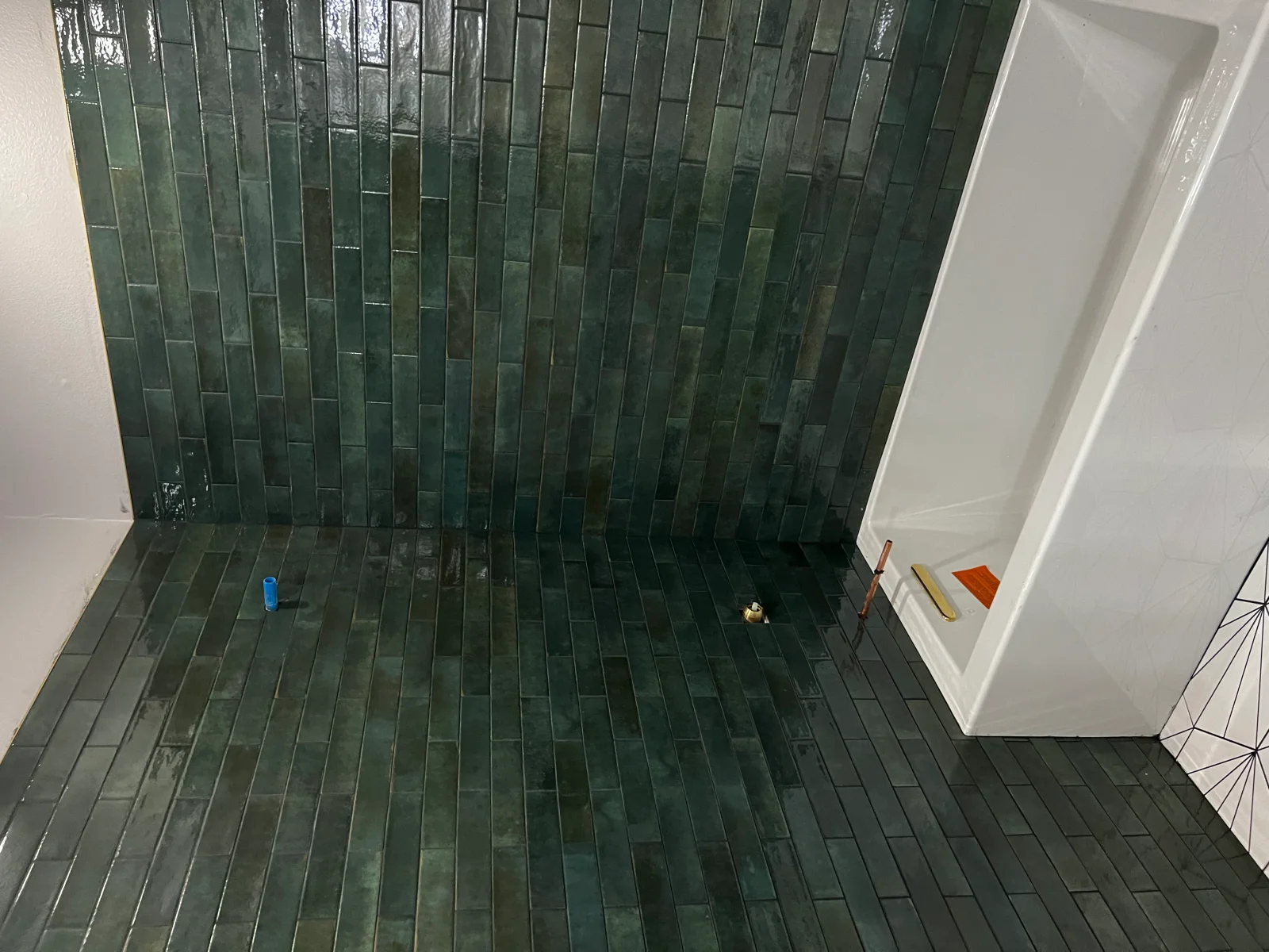 Dark green subway tile shower with running bond pattern, white trim frame
