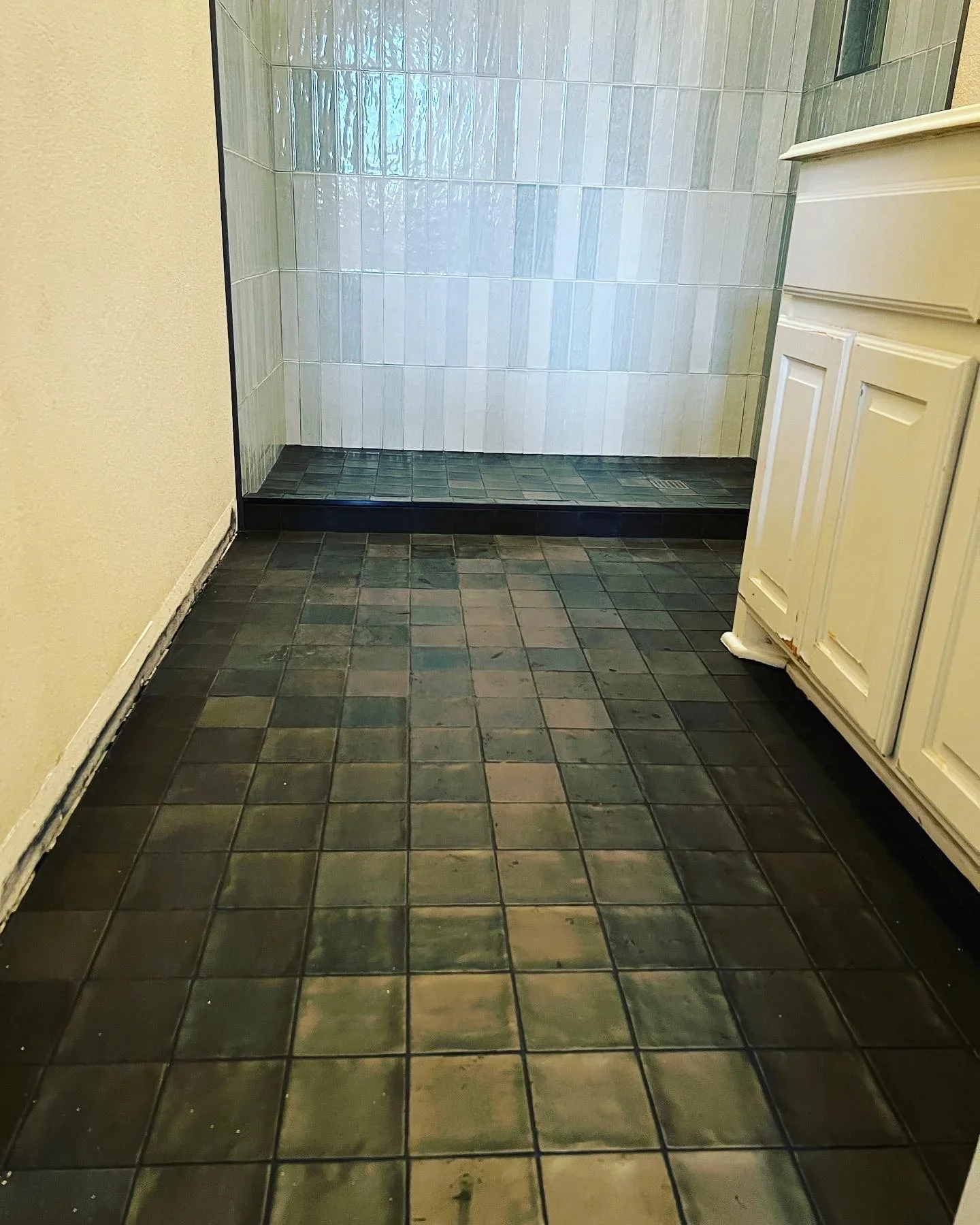 Shower enclosure with vertical subway tile walls and dark slate floor tile